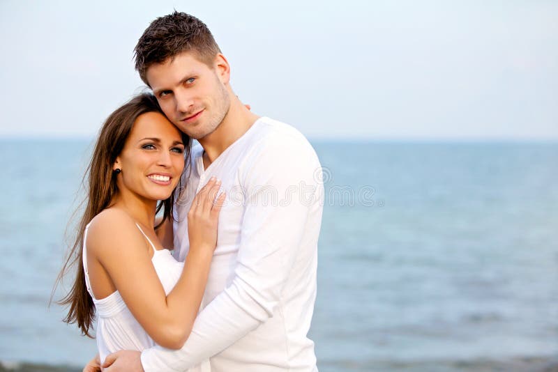 Young couple, posing backlit in a sunset on the beach Stock Photo by  wirestock