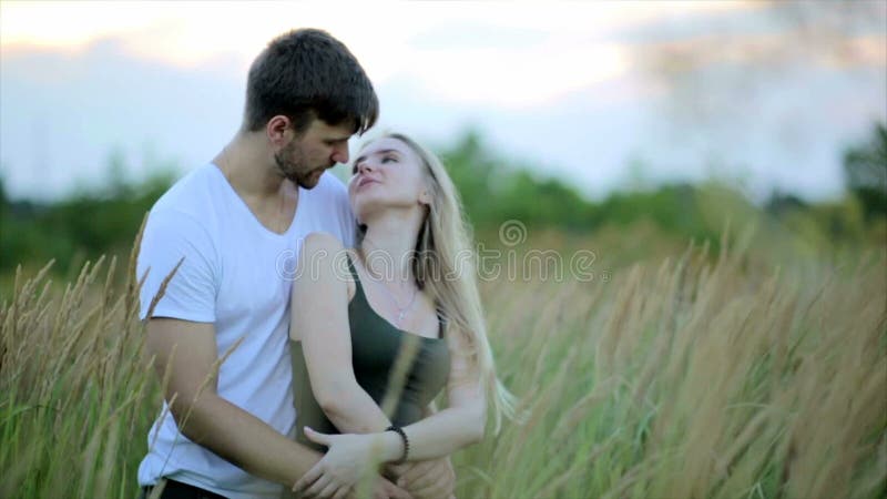 Romantic Couple at Sunset. Two people in love at sunset or sunrise. Man and woman kissing on field