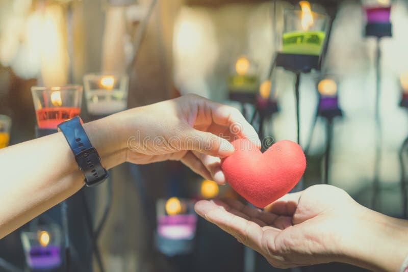 Romantic couple on valentines day. Happy joyful woman giving man heart shape little pillow in a candle light.In the afternoon