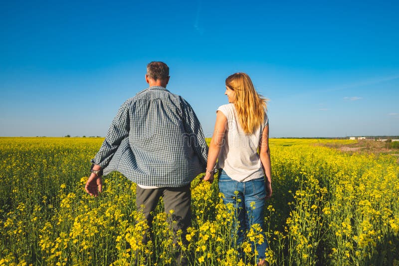 Romantic Couple Is Walking Through The Field Of Yellow Flowers Stock 