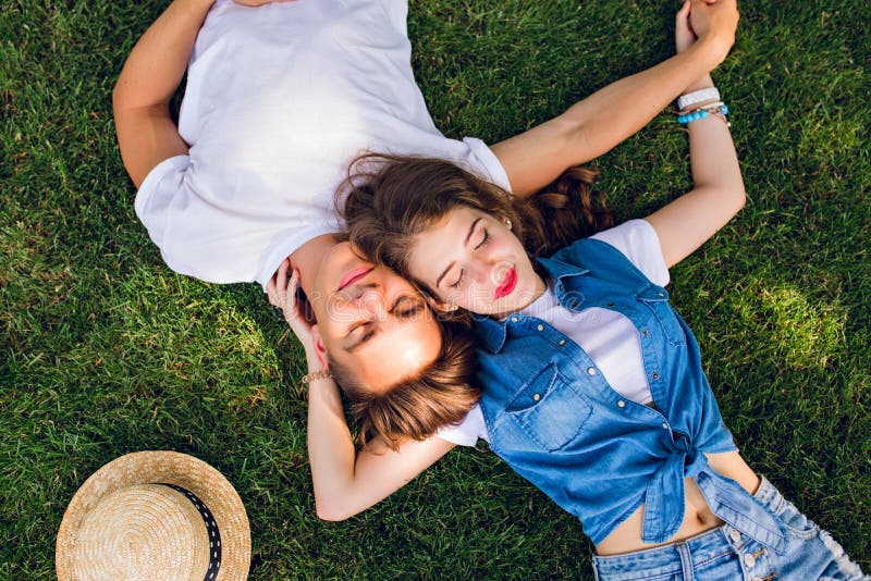 Romantic couple of young people lying on grass in park. They lay on the shoulders of each other and hold hands together stock photography Romantic couple of young people lying on grass in park. They lay on the shoulders of each other and hold hands together stock photography