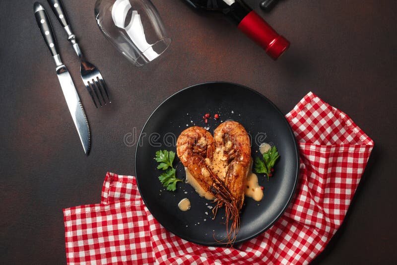 Romantic dinner with heart-shaped shrimps and wine on a brown background. Top view