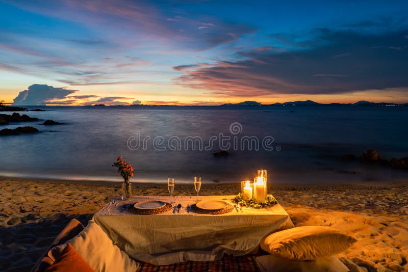 Romantic Dinner Table set beside the beach in the sunset twilight time, at Munnok Island, Thailand