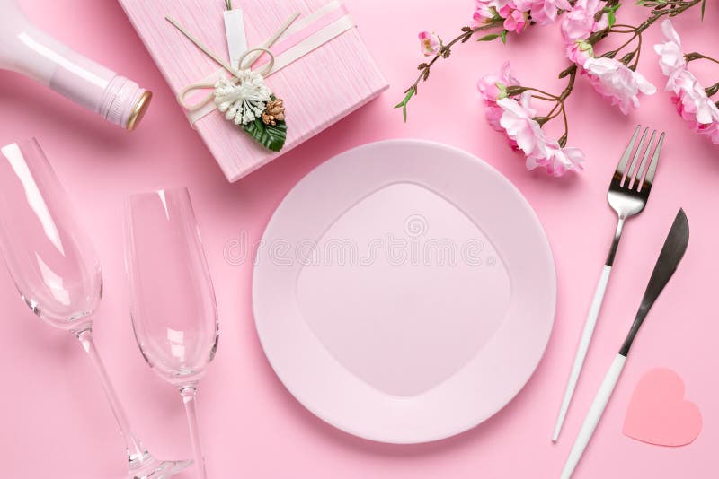 Romantic dinner, table setting on Valentine`s Day. Dating concept, love. Spring flowers, empty plate, glasses, champagne, gift bo