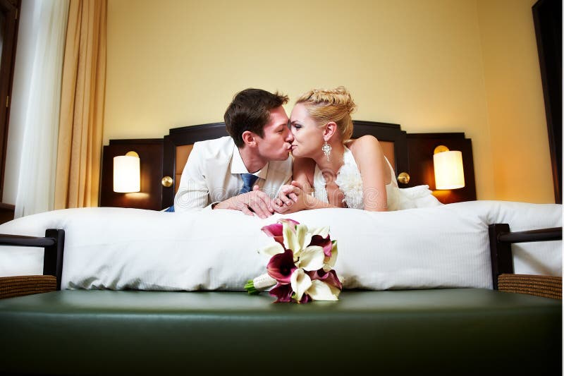 Romantic kiss happy bride and groom in bedroom