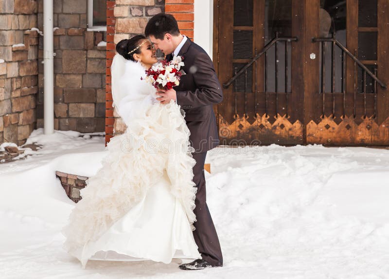 Romantic kiss happy bride and groom on winter wedding day