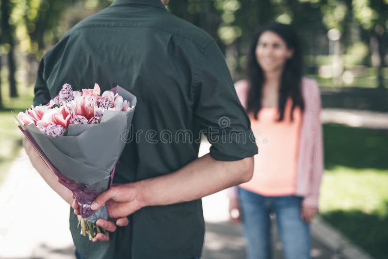 Romantic man hiding flowers and making surprise for girlfriend stock photos Romantic man hiding flowers and making surprise for girlfriend stock photos