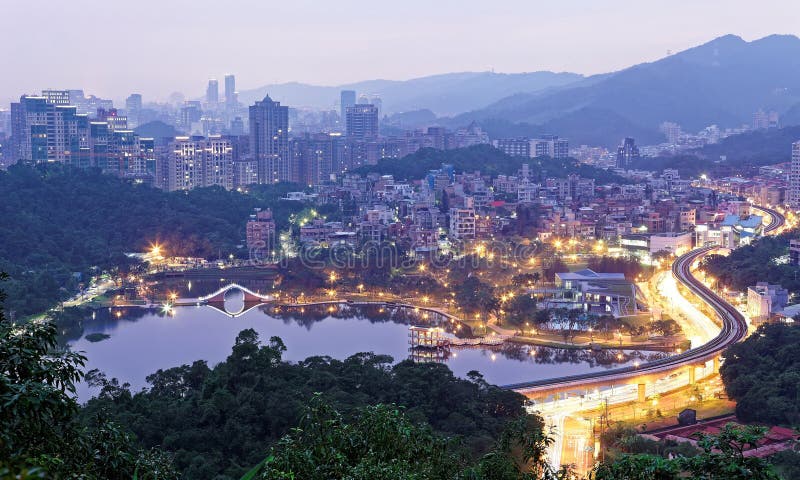 Romantic night aerial view of Da-Hu Community Park at dusk with an oriental arch bridge over the lake