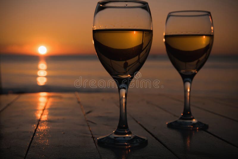 Romantic outdoor activity. Two glasses with white wine in an outdoor restaurant with sunset sea view, relaxation concept for two