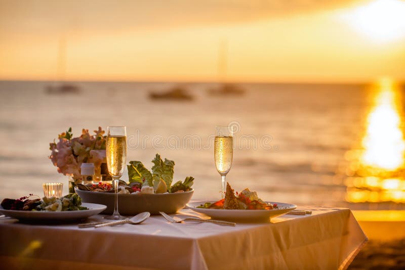 Romantic Sunset Dinner On The Beach Table Set For Two With Luxurious Food Glasses Of Champaign