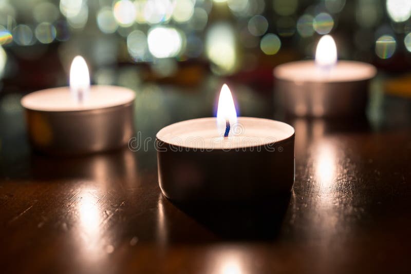 3 Romantic Tea Lights for Dinner on Wooden Table with Bokeh at Night
