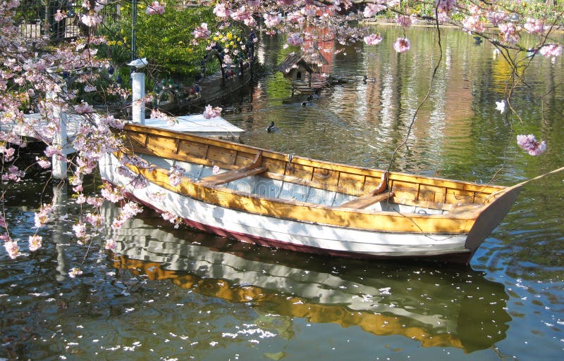 Romantic view of a wooden boat surrounded by a sea of ​​flowers in a small lake - in Tivoli in Copenhagen in Denmark. Romantic view of a wooden boat surrounded by a sea of ​​flowers in a small lake - in Tivoli in Copenhagen in Denmark