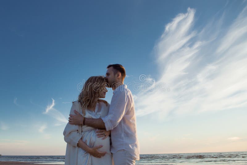 Romantic walk on the beach, waiting for a baby. Happy young couple hugging tummy, spending time by the sea. royalty free stock image Romantic walk on the beach, waiting for a baby. Happy young couple hugging tummy, spending time by the sea. royalty free stock image