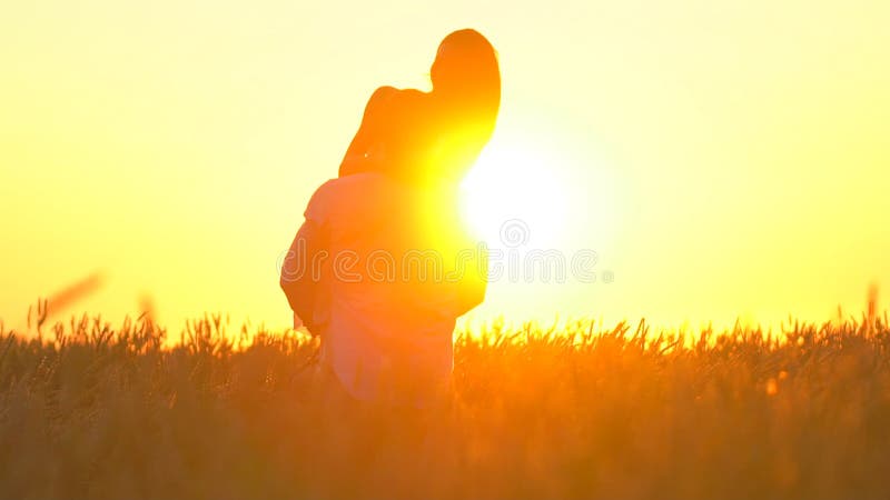 Romantic young happy couple silhouette in golden wheat field at sunset. Woman is running to her man, they hugging and