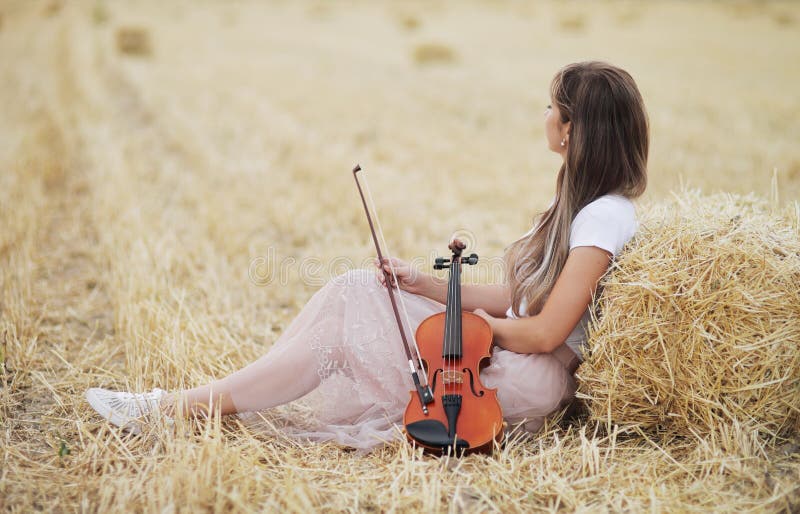 Romantic Young Woman with Flowing Hair Holding a Violin in Her Hand in a  Field Stock Photo - Image of package, fiddle: 191735006