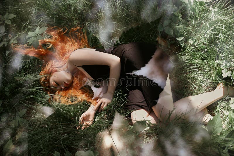 Romantische Frau mit dem roten Haar, das im Wald im Gras liegt Ein Mädchen den im hellen schwarzen Kleiderschlaf und -träumen in lizenzfreie stockbilder Romantische Frau mit dem roten Haar, das im Wald im Gras liegt Ein Mädchen den im hellen schwarzen Kleiderschlaf und -träumen in lizenzfreie stockbilder