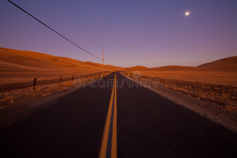 Two lane country road at dusk in farm land country - idyllic dusk / dawn lighting. Two lane country road at dusk in farm land country - idyllic dusk / dawn lighting.