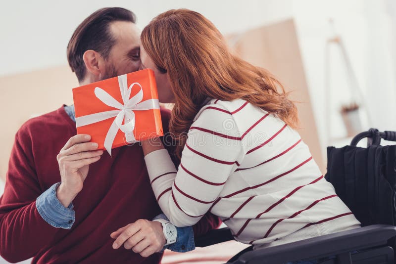 Romantische Paare, die hinter dem Geschenk und dem Küssen sich verstecken lizenzfreie stockbilder Romantische Paare, die hinter dem Geschenk und dem Küssen sich verstecken lizenzfreie stockbilder