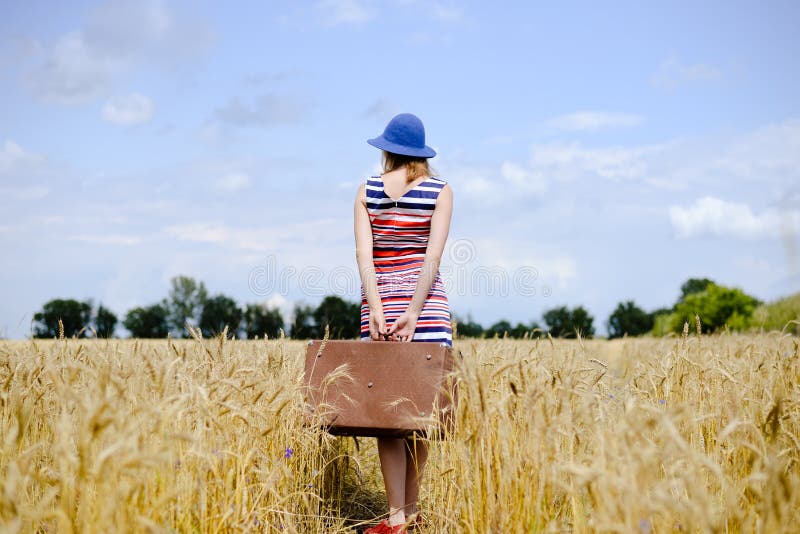 Romantische vrouw die hoed met koffer het lopen dragen stock foto Romantische vrouw die hoed met koffer het lopen dragen stock foto