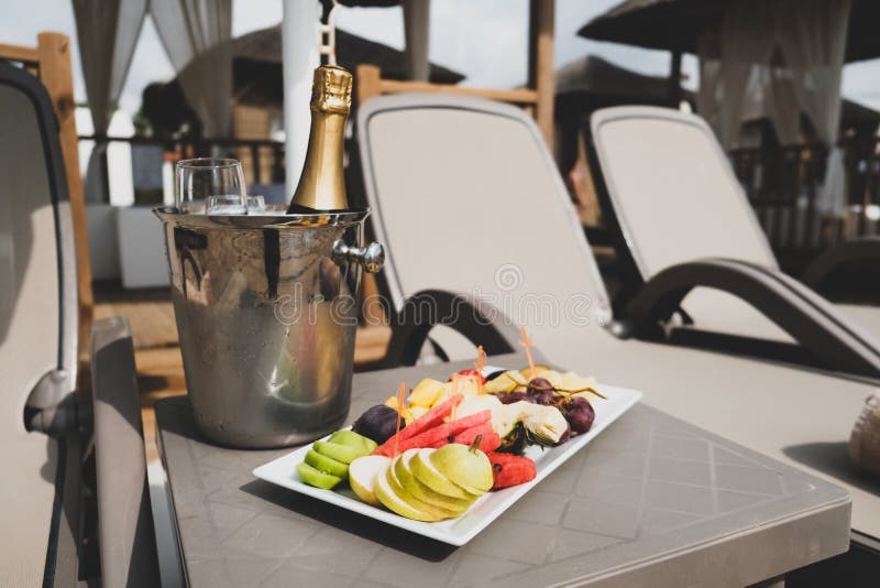 Romantischer Tag am Strand. Begehung des Jahrestags oder der Flitterwochen Nähe Pool oder Küste. Flasche Champagner oder Wein im Eiseimer und Fruchtplatte in vip-Aufenthaltsraum mit sunbeds. Luxuswochenendenpaarflucht