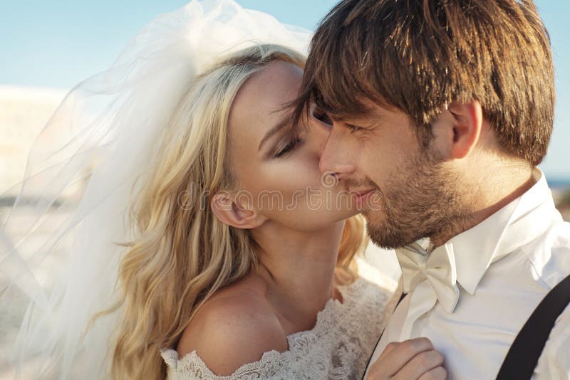 Romantisches Bild der jungen Braut ihren Ehemann küssend lizenzfreies stockbild Romantisches Bild der jungen Braut ihren Ehemann küssend lizenzfreies stockbild