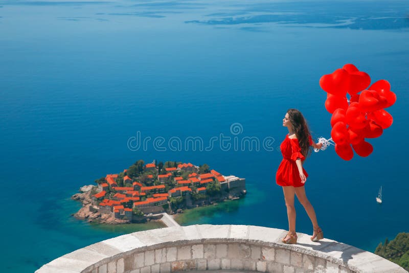 Romantisk flicka i röd klänning över den Sveti Stefan ön i Budva, Mo