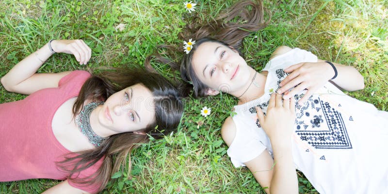 Romantisk lycklig tonåringvänflicka som ligger på blommaäng royaltyfri fotografi Romantisk lycklig tonåringvänflicka som ligger på blommaäng royaltyfri fotografi