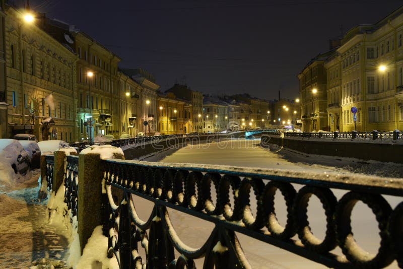 Romantisk nattvinterstad med snow och en djupfryst flod arkivfoton