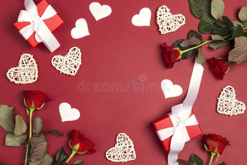 Romantisk ram av gåvor, rosa blommor och dekorativa hjärtor på röd bakgrund Stället för text, överträffar ner sammansättning royaltyfria bilder Romantisk ram av gåvor, rosa blommor och dekorativa hjärtor på röd bakgrund Stället för text, överträffar ner sammansättning royaltyfria bilder