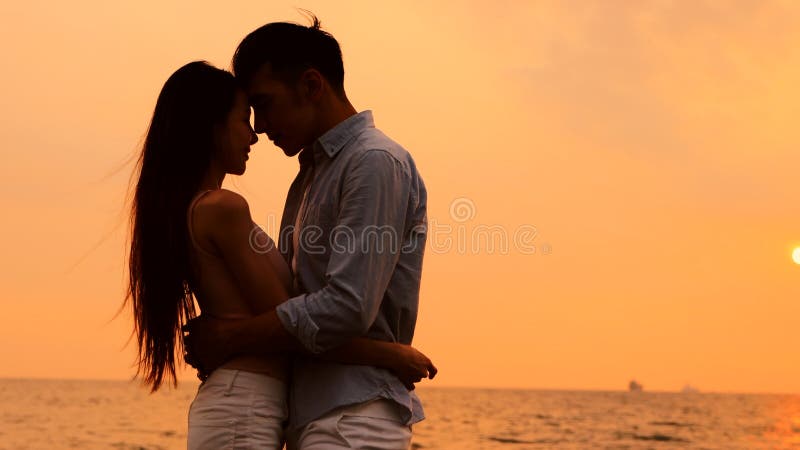 Romantisk ung kram på stranden vid solnedgången