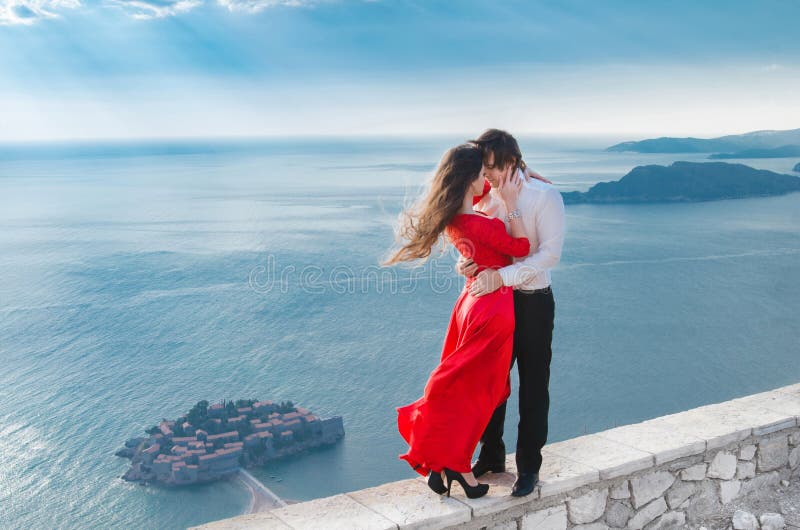 Romantiska omfamna par bredvid det blåa havet framme av Sveti Stef royaltyfria foton Romantiska omfamna par bredvid det blåa havet framme av Sveti Stef royaltyfria foton