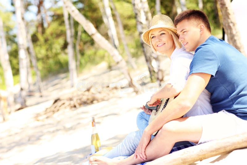 Romantiska par som spelar gitarren på stranden arkivfoton Romantiska par som spelar gitarren på stranden arkivfoton