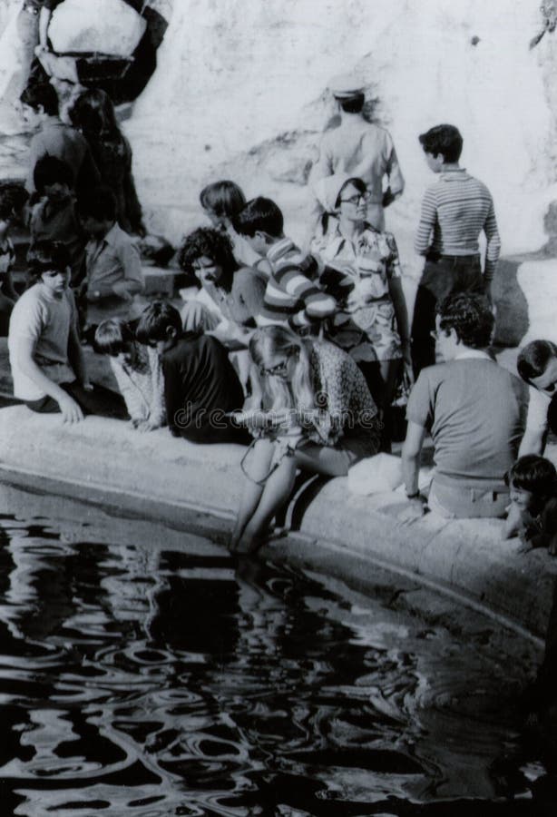 ROME, ITALIË, 1970 - jongelui, blonde vrouwelijke toerist leest stil een boek terwijl het verfrissen van haar voeten in de Trevi stock foto's ROME, ITALIË, 1970 - jongelui, blonde vrouwelijke toerist leest stil een boek terwijl het verfrissen van haar voeten in de Trevi stock foto's