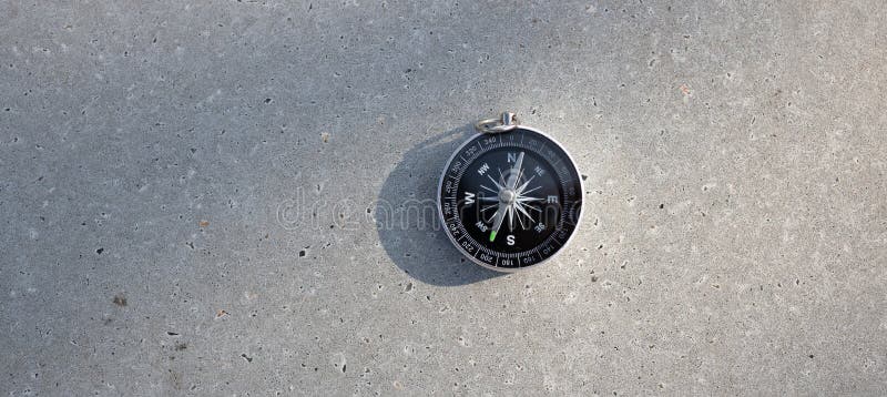 Rond stijlvol kompas op betonnen achtergrondzoekrichting in zomerbergen.