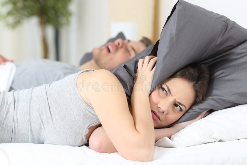 Ronflement d'homme et ses oreilles de bâche d'épouse image stock Ronflement d'homme et ses oreilles de bâche d'épouse image stock