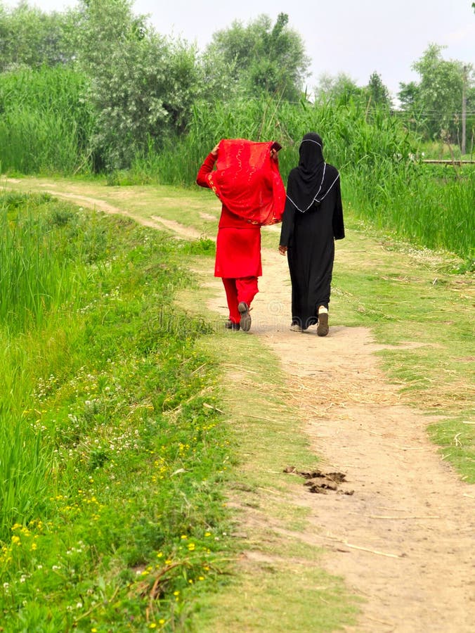 Two ladies dressed in red and black on the shore of the Dal lake in Srinagar, Kashmir, Northern India. Two ladies dressed in red and black on the shore of the Dal lake in Srinagar, Kashmir, Northern India.