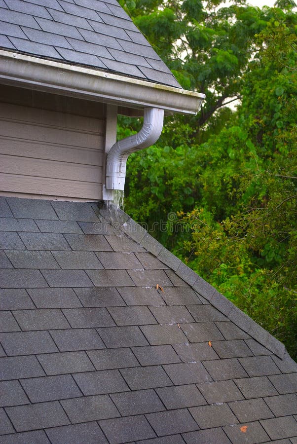 Roof gutter and shingles on a rainy day royalty free stock photography