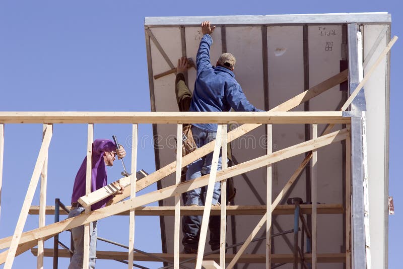Lavoratori edili ponendo la prima sezione del tetto di una nuova casa in costruzione.