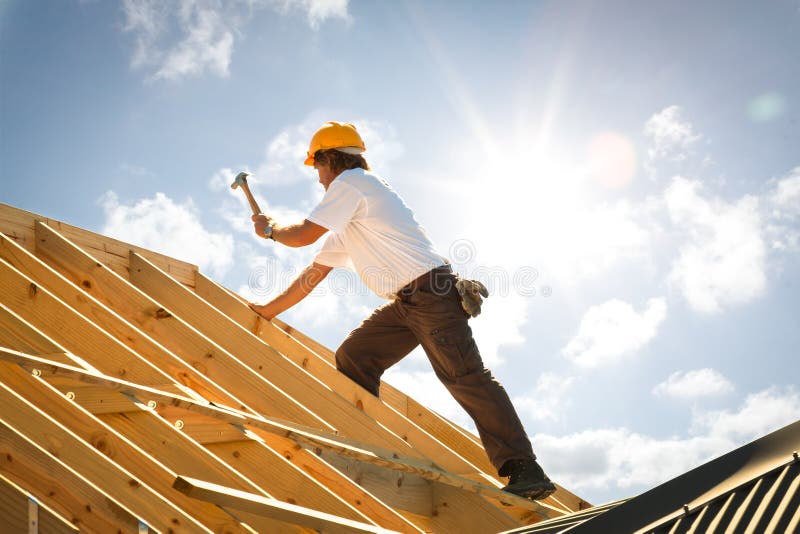 Roofer tesár práce na strešných konštrukciách vonku s sunflare a modrú oblohu a kopírovať priestor.