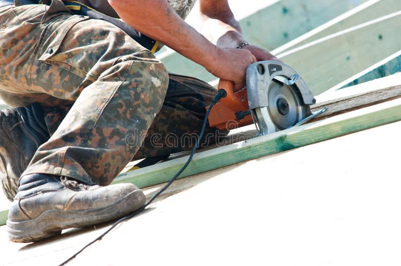 Legs and arms of worker on rooftop using rotary drill. Legs and arms of worker on rooftop using rotary drill.