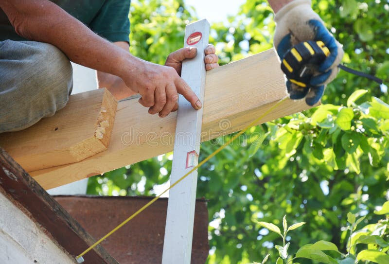 Roofers measuring roof wooden beam installation with measuring tape and spirit level. Roofing construction photo