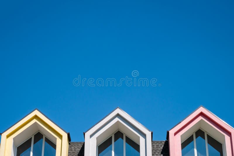 Roofline and pointed attic windows against blue sky
