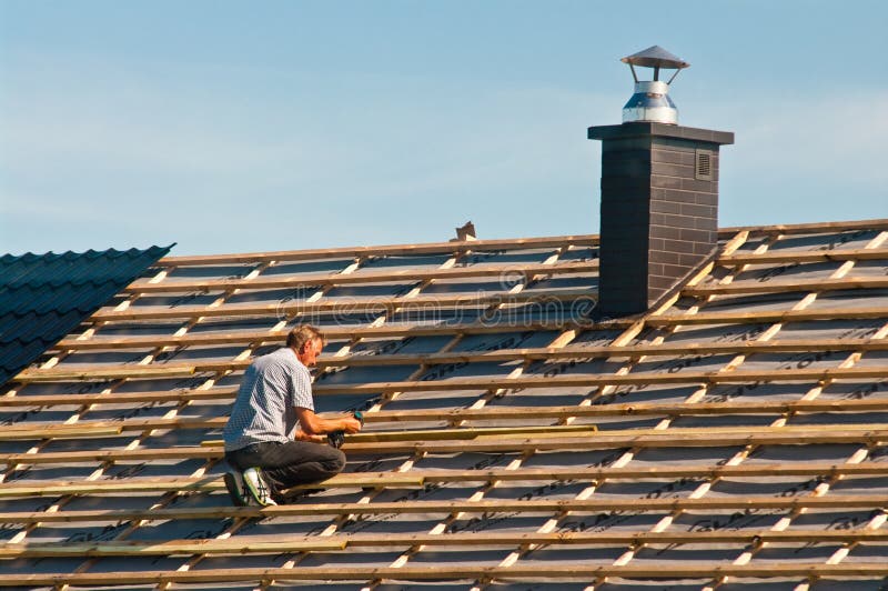 Rooftop worker installing new metal tiles on a house