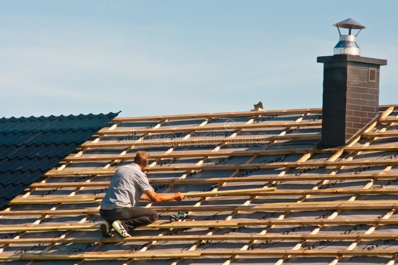 Rooftop worker installing new metal tiles on a house