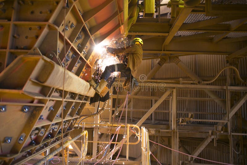 Rope access miner wearing safety harness helmet uniform working at height on rope commencing gouging