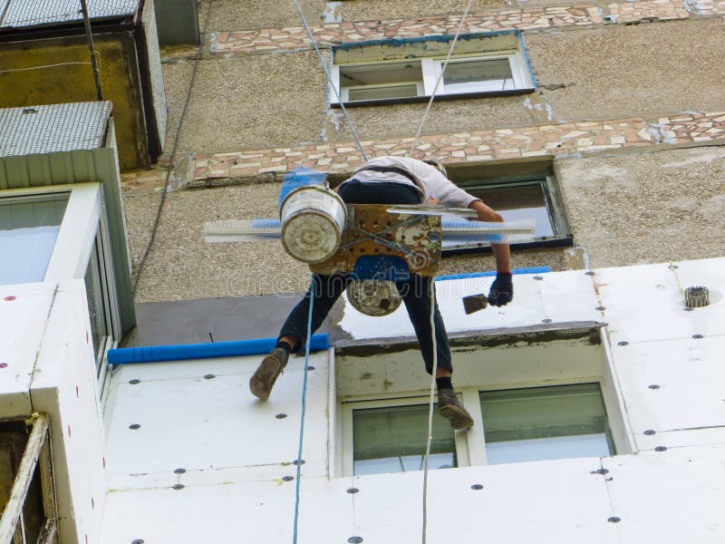 Rope Access Worker Spreading Mortar Over Styrofoam Insulation Stock