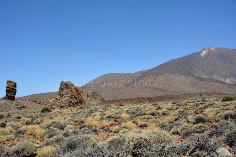 The bizarrely shaped Roque Cinchado rock of volcanic rock in Teide National Park on the Canary Island of Tenerife, Spain. With views of Mount Teide and blue skies. The bizarrely shaped Roque Cinchado rock of volcanic rock in Teide National Park on the Canary Island of Tenerife, Spain. With views of Mount Teide and blue skies