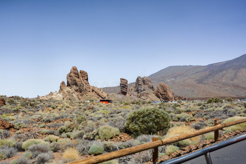 The bizarrely shaped Roque Cinchado rock , with parked cars, of volcanic rock in Teide National Park on the Canary Island of Tenerife, Spain. The bizarrely shaped Roque Cinchado rock , with parked cars, of volcanic rock in Teide National Park on the Canary Island of Tenerife, Spain