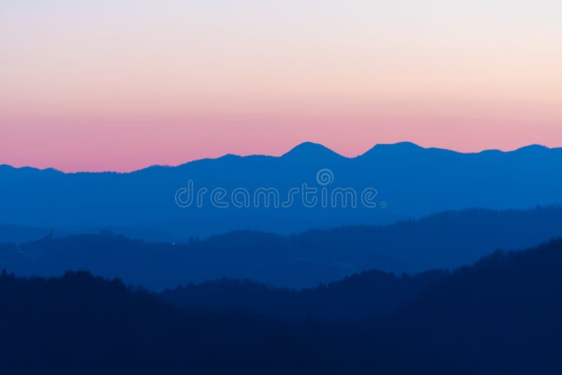 Rosa bonito e nuances azuis da cor do céu e dos montes crepusculares após o por do sol fotografia de stock Rosa bonito e nuances azuis da cor do céu e dos montes crepusculares após o por do sol fotografia de stock
