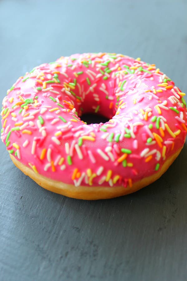 Rosa Donut mit besprüht auf schwarzem Hintergrund stockbild Rosa Donut mit besprüht auf schwarzem Hintergrund stockbild